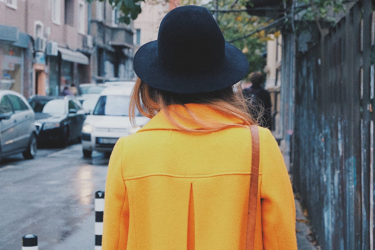 A bright wool coat and a felt hat. The shoulder is soft and the line is long.